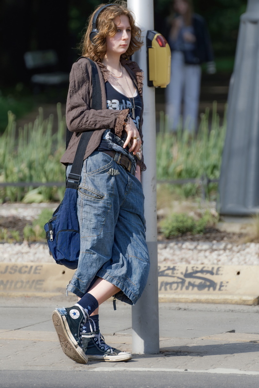 14 - A person styling blue denim jorts, a brown textured jacket, and high-top sneakers, reflecting a trend of casual, vintage-inspired street fashion